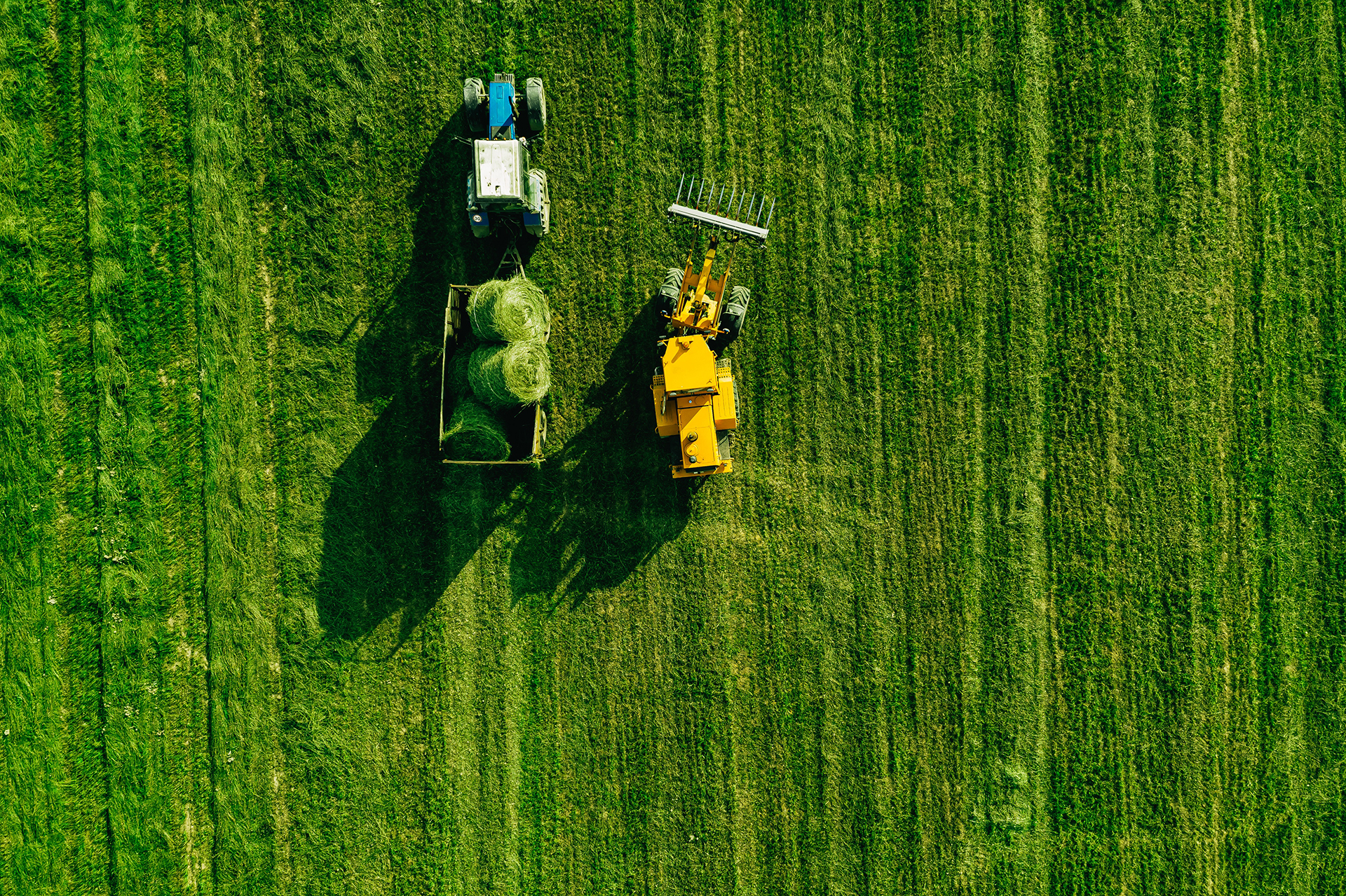 aerial-view-green-grass-harvest-field-with-tractor-moving-hay-bale_1.jpg